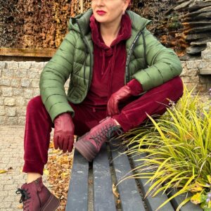 Izabela Kuligowska stylizka w sportowej stylizacji: zielona puchowa kurtka i welurowy bordowy dres, siedząca na ławce, moda casualowa na jesień.