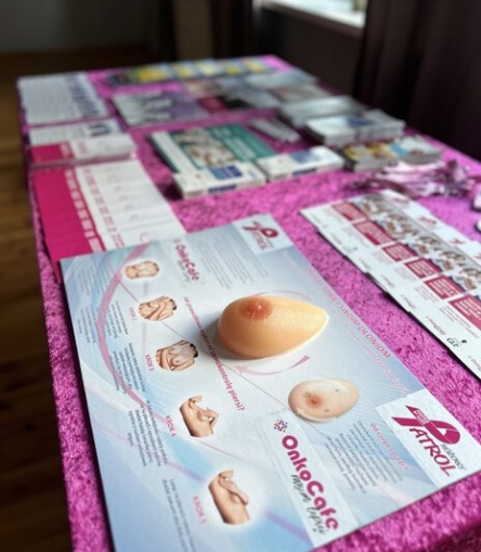 Materiały edukacyjne OnkoCafe dotyczące samokontroli piersi oraz fantomy szkoleniowe na różowym stole na evencie "Różowy Patrol"