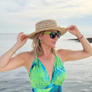 Izabela Kuligowska stylizka w kapeluszu i kostiumie kąpielowym na tle morza, letnia stylizacja plażowa.