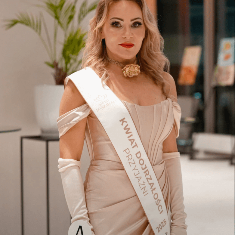 Izabela Kuligowska stylizka w eleganckiej, beżowej sukni gorsetowej z szarfą "Kwiat Dojrzałości Przyjaźni" na evencie, stylizacja wieczorowa.
